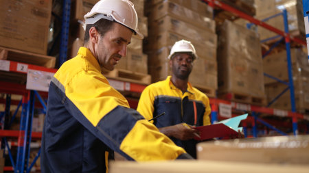 Two warehouse workers are reviewing the list of items based on the documentationの写真素材