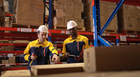Two warehouse workers are reviewing the list of items based on the documentationの写真素材