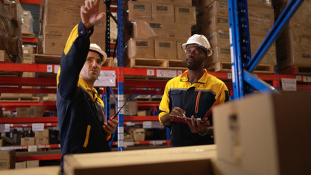 Two warehouse workers are reviewing the list of items based on the documentationの写真素材