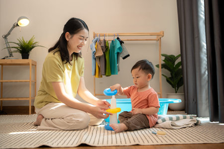 Little boy with mom playing with toys before bathingの写真素材