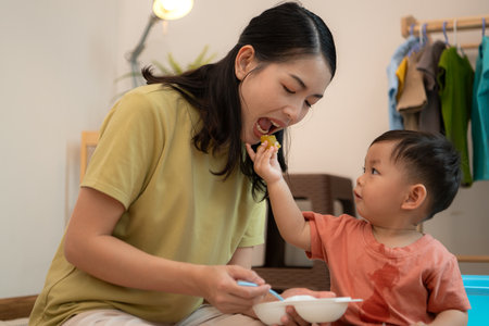 Little boy with breakfast with mom feeding him before bathingの写真素材