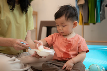 Little boy with breakfast with mom feeding him before bathingの写真素材