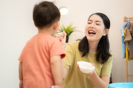 Little boy with breakfast with mom feeding him before bathingの写真素材