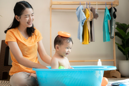 Mom and little child with taking a shower and dressing at home in the morningの写真素材