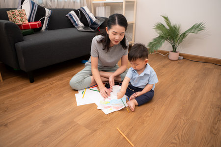 While in vacation at home, a mother engages in drawing activities with little kidの写真素材