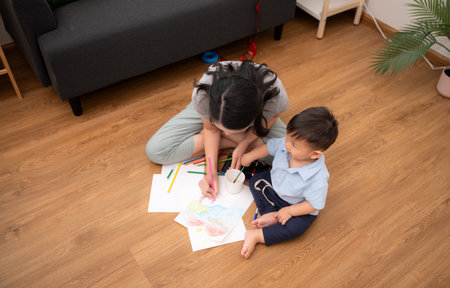 While in vacation at home, a mother engages in drawing activities with little kidの写真素材