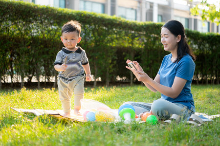 While in vacation at home, a mother engages in activities with little kid in the parkの写真素材