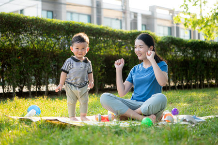 While in vacation at home, a mother engages in activities with little kid in the parkの写真素材