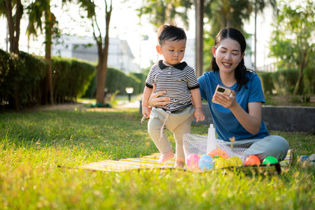 While in vacation at home, a mother engages in activities with little kid in the parkの写真素材