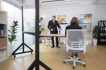 In a contemporary office, boss and assistant are on a mission to monitor the progress of a business projectの写真素材