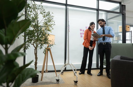 In a contemporary office, two young entrepreneurs are on a mission to generate ideas and establish a business projectの写真素材