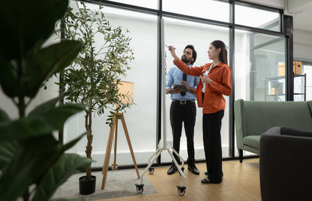 In a contemporary office, two young entrepreneurs are on a mission to generate ideas and establish a business projectの写真素材