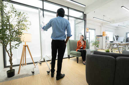 In a contemporary office, two young entrepreneurs are on a mission to generate ideas and establish a business projectの写真素材