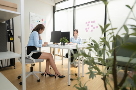 In a contemporary office, two young woman entrepreneurs are on a mission to generate ideas and establish a business projectの写真素材