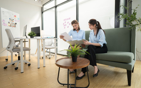 In a contemporary office, two young woman entrepreneurs are on a mission to generate ideas and establish a business projectの写真素材