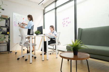 In a contemporary office, two young woman entrepreneurs are on a mission to generate ideas and establish a business projectの写真素材