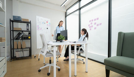 In a contemporary office, two young woman entrepreneurs are on a mission to generate ideas and establish a business projectの写真素材