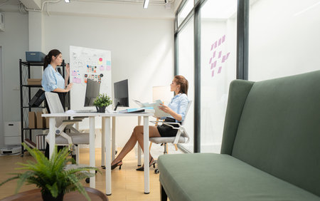 In a contemporary office, two young woman entrepreneurs are on a mission to generate ideas and establish a business projectの写真素材