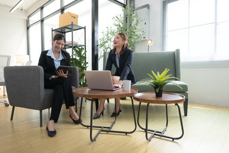 In a contemporary office, two young woman entrepreneurs are on a mission to generate ideas and establish a business projectの写真素材