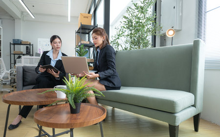In a contemporary office, two young woman entrepreneurs are on a mission to generate ideas and establish a business projectの写真素材