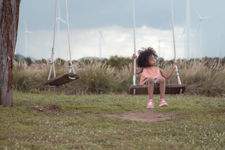 Little girl with swinging on a swing in picnic camping family day in wind turbine fieldの写真素材