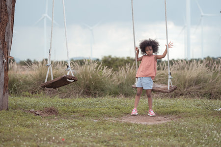 Little girl with swinging on a swing in picnic camping family day in wind turbine fieldの写真素材