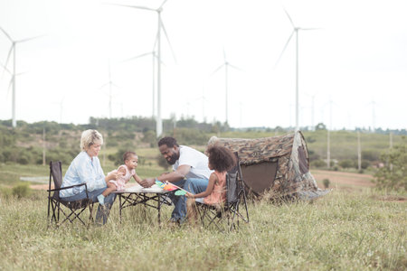 Family picnic camping in the wind turbine fieldの写真素材
