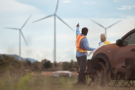 An engineer father and his family do a little more work in front of a car before getting off work in a wind turbine fieldの写真素材