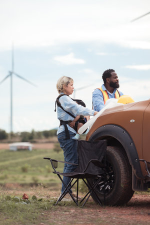 An engineer father and his family do a little more work in front of a car before getting off work in a wind turbine fieldの写真素材