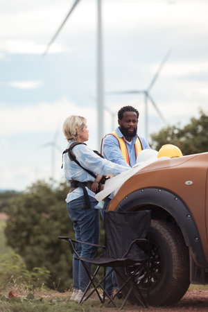 An engineer father and his family do a little more work in front of a car before getting off work in a wind turbine fieldの写真素材