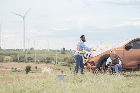 An engineer father and his family do a little more work in front of a car before getting off work in a wind turbine fieldの写真素材