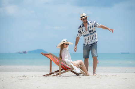 Young couple on vacation on a white sandy beach, clear sky and seaの写真素材