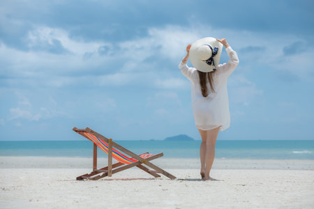 Young woman on vacation on a white sandy beach, clear sky and seaの写真素材
