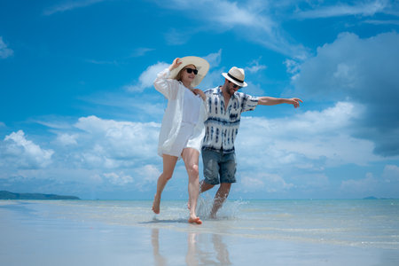 Young couple on vacation on a white sandy beach, clear sky and seaの写真素材