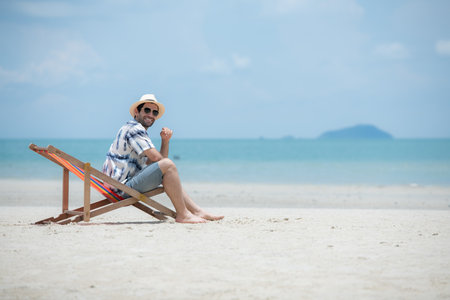Young man on vacation on a white sandy beach, clear sky and seaの写真素材