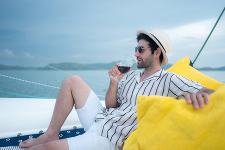 A young man is enjoying his seaside adventure aboard a yachtの写真素材