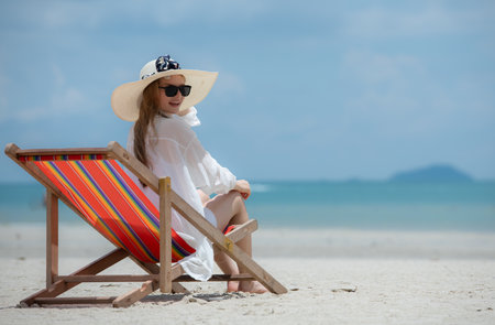 Young woman on vacation on a white sandy beach, clear sky and seaの写真素材
