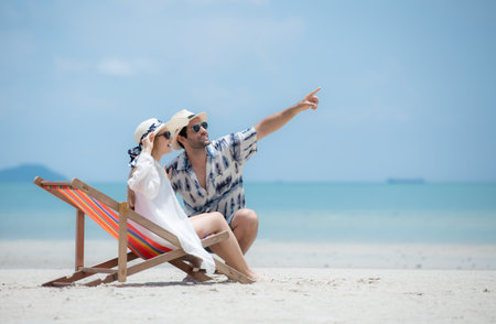 Young couple on vacation on a white sandy beach, clear sky and seaの写真素材