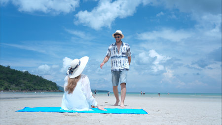 Young couple on vacation on a white sandy beach, clear sky and seaの写真素材