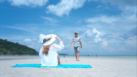 Young couple on vacation on a white sandy beach, clear sky and seaの写真素材