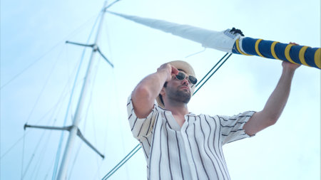 A young man is enjoying his seaside adventure aboard a yachtの写真素材