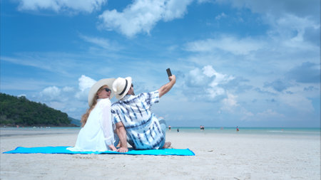 Young couple on vacation on a white sandy beach, clear sky and seaの写真素材