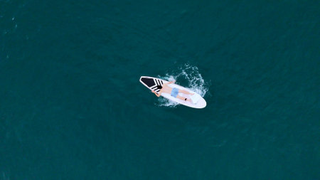 A young man is enjoying his ocean adventure aboard a yacht and surfboardの写真素材