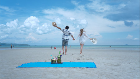 Young couple on vacation on a white sandy beach, clear sky and seaの写真素材