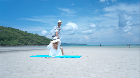 Young couple on vacation on a white sandy beach, clear sky and seaの写真素材