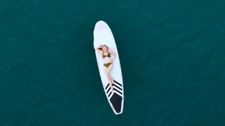 A young woman is enjoying her ocean adventure aboard a surfboardの写真素材