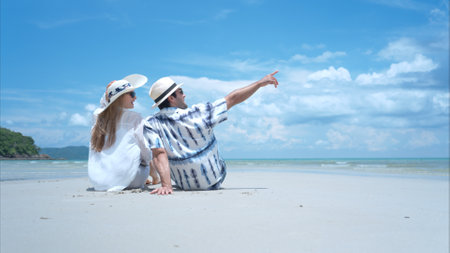 Young couple on vacation on a white sandy beach, clear sky and seaの写真素材