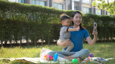 While in vacation at home, a mother engages in activities with little kid in the parkの写真素材