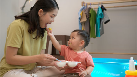 Little boy with breakfast with mom feeding him before bathing himの写真素材