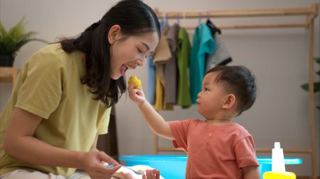 Little boy with breakfast with mom feeding him before bathing himの写真素材